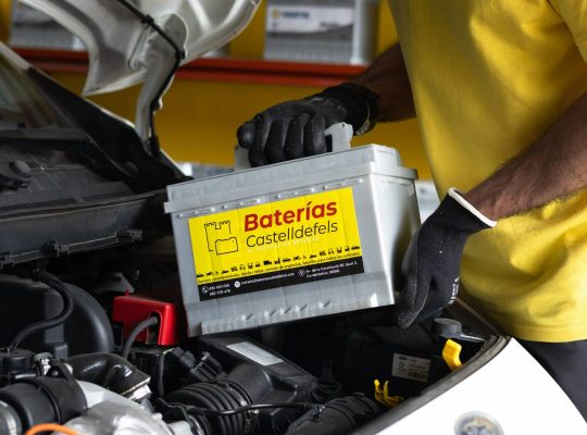 Un electromecanico está cambiando la batería para un coche